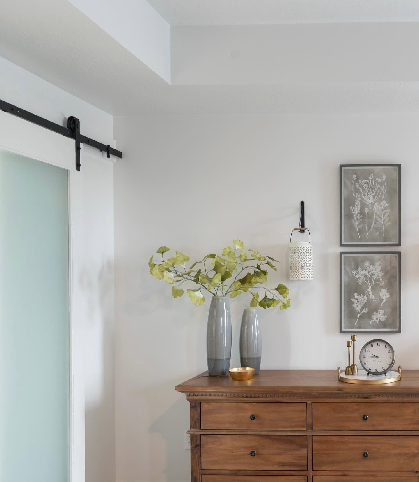 Wood dresser styled with grey vases and ginkgo branches beside a frosted sliding door