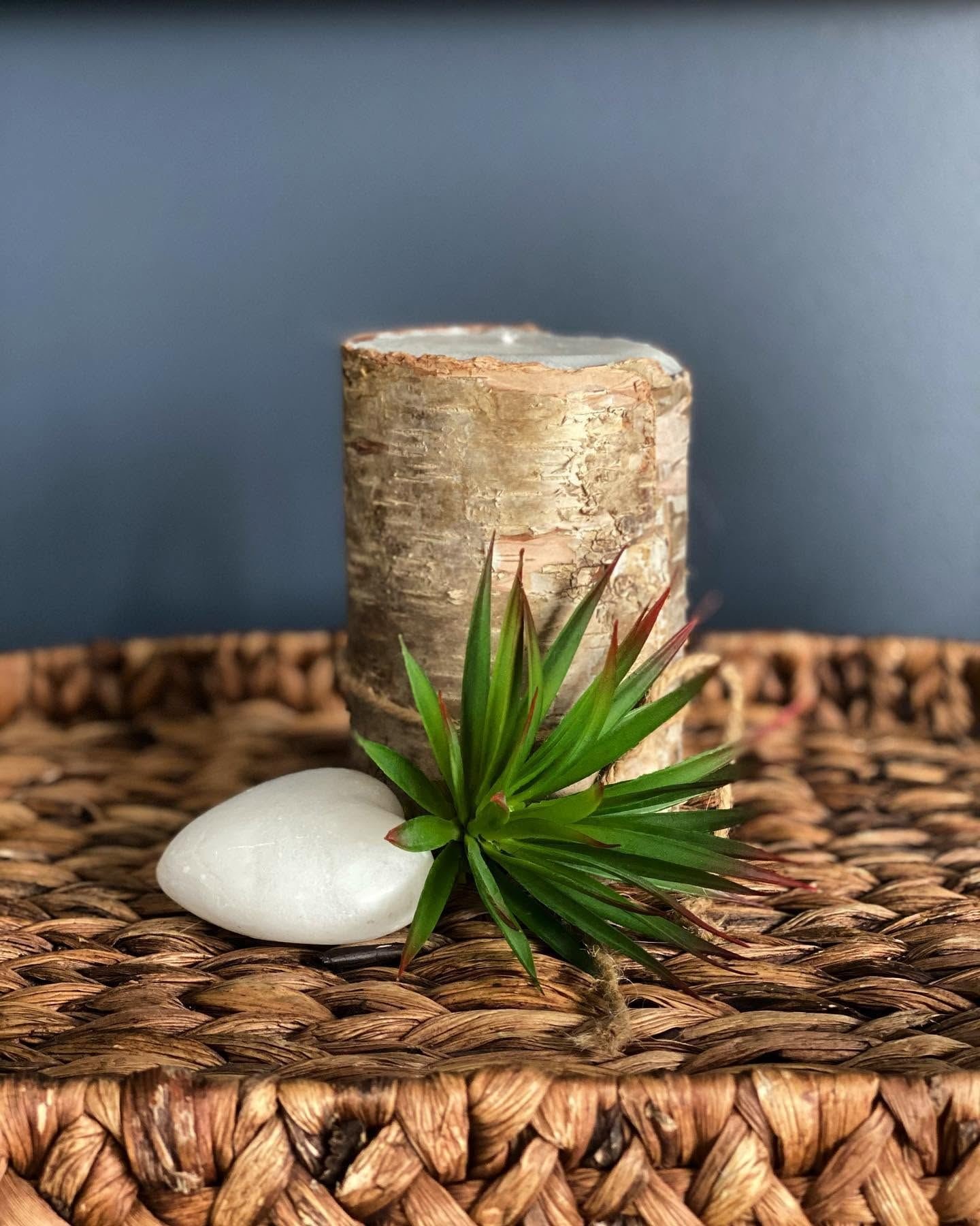 Birch-bark candle with a stone heart on a woven tray